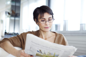 Woman reading a news paper with glasses before surgery